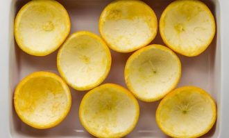 Апельсины хорошо промойте в теплой воде, разрежьте пополам, извлеките аккуратно мякоть, разместите чашечки в лоток и отправьте их в холодильник.