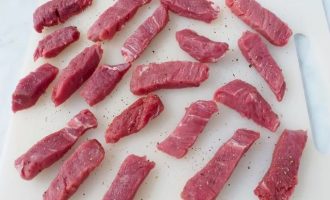 Нарежьте мясо на тонкие полоски для бефстрогонова