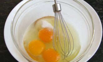 В удобную миску добавьте три яйца, соль, сахар и все хорошо размешайте при помощи венчика.