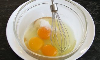 В удобную посуду разбейте три яйца, всыпьте по указанной рецептуре сахар и соль. При помощи венчика слегка взбейте все три ингредиента.