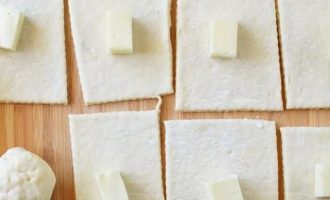 Поместите кусочек сыра в центр каждого куска теста и оберните тестом, чтобы сыр был покрыт со всех сторон.
