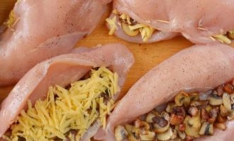 Начините 4 куриные грудки сыром, беконом и грибами, оставив немного для посыпки