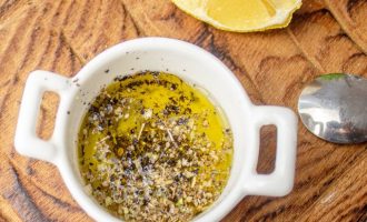Приготовьте соус-заправку из указанных ингредиентов. Для этого в небольшую миску налейте оливковое масло, добавьте свежевыжатый лимонный сок, специи, приправки и все смешайте.