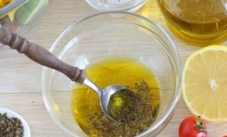 Теперь приготовьте ароматную заправку. В стеклянную мисочку вылейте оливковое масло, свежевыжатый лимонный сок, соль, перец и сушеный орегано. Все хорошо перемешайте и дайте заправке немного постоять.