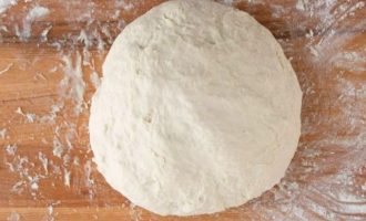 Выложите тесто на посыпанную мукой доску и начните месить около 10 минут, добавляя муку, когда тесто не станет липким.