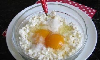 В удобную миску высыпать творог (у меня он домашний), разбить два яйца, всыпать сахар и соль.