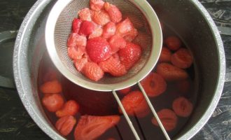 Процедите ягодный компот через сито. Плотную часть клубники удалите.