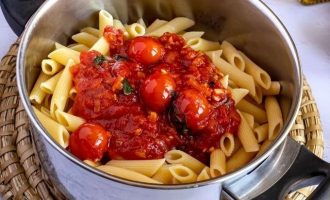 Выложите отварные макароны в кастрюлю и добавьте часть отложенного томатного соуса, чтобы макароны приобрели аромат и пропитались соусом