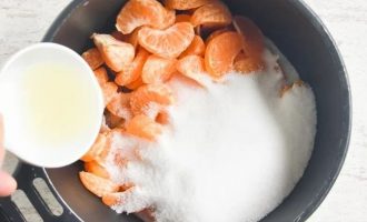 Подготовленные мандарины поместите в кастрюлю, засыпьте сахаром и добавьте лимонный сок