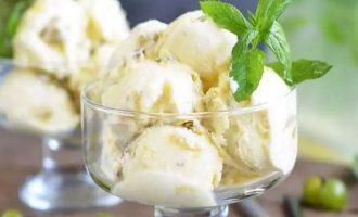 Выложите готовое мороженое из крыжовника в креманки, используя ложку - выталкиватель, чтобы получились красивые шарики и украсьте свежими веточками мяты