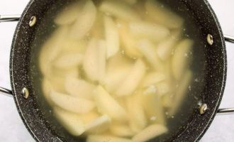 Картофельные дольки переложите в кастрюлю, залейте горячей водой, поставьте на плиту и варите, пока они не станут мягкими. В процессе варки добавьте соль.