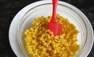 Теперь в миску выложите консервированную кукурузу, но предварительно слейте жидкость.