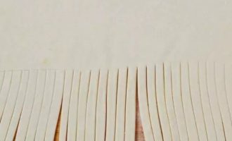 После того как тесто поднялось, пробейте тесто, чтобы выпустить излишки газа. Раскатать на слегка присыпанной мукой поверхности и нарезать полосками половину теста.