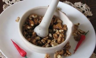 Грецкие орехи освободите от скорлупы, зерна поделите на несколько частей, а потом поместите в ступку и при помощи пестика хорошо растолките.