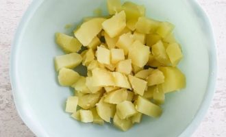 После того, как картофель остынет, очистите от кожицы и нарежьте на кубики и выложите в миску
