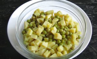 Теперь выложите в салатную миску нарезанный картофель и зеленый горошек. Перед добавлением из банки слейте рассол.