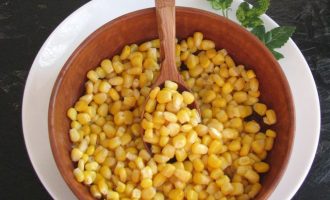 Консервированную кукурузу извлеките из банки, слейте жидкость, а зерна высыпьте в салатницу.