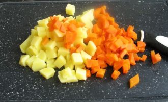 Далее поставьте варить картофель и морковь в кожуре. После охлаждения очистите и нарежьте мелкими кубиками.