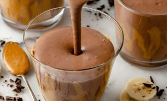 Разлейте шоколадный смузи с арахисовым маслом и бананом по высоким стаканам