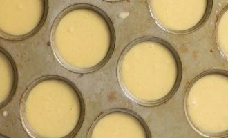 Смажьте противень с 12 формочками и распределите тесто в каждую из них поровну