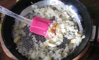 Сковородку разогрейте вместе с растительным маслом и спассеруйте репчатый лук до слегка поджаристого колера.