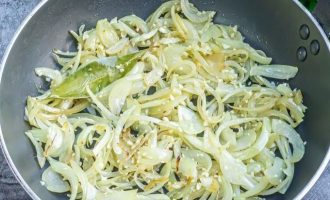 В большой сковороде разогрейте оливковое масло и, когда оно нагреется, добавьте нарезанный полукольцами лук вместе с лавровым листом и поджарьте