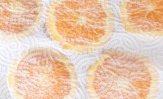 Разложите кружочки апельсина на бумажное полотенце и накройте вторым бумажным полотенцем. Осторожно нажмите и дайте высохнуть в течение 10 минут.