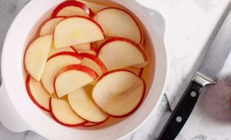 Наполовину наполните большую миску холодной водой и добавьте лимонный сок. Разрежьте яблоки пополам, удалите сердцевину и нарежьте яблоки тонкими ломтиками. Не очищайте яблоки от кожуры. Кожица придаст яблочным розам красный цвет. Сразу же поместите нарезанные яблоки в миску и погрузите в воду с лимоном, чтобы предотвратить потемнение.
