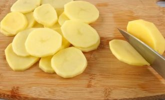Первым долгом займитесь подготовкой картофеля. Для этого его очистите и нарежьте на тонкие кружочки, толщиной около 3 мм