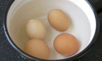Яйца достаньте из холодильника, пусть постоят при комнатной температуре, а после залейте холодной водой, добавьте соль и сварите вкрутую. Время варки потребуется 10-11 минут. Затем укутайте их в кухонное полотенце и через 15 минут очистите.