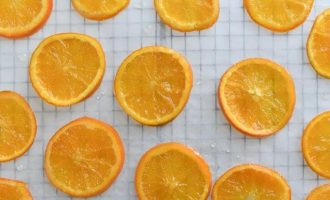 Разложите кружочки апельсинов на листе вощеной бумаги, чтобы они стекали и дайте им остыть
